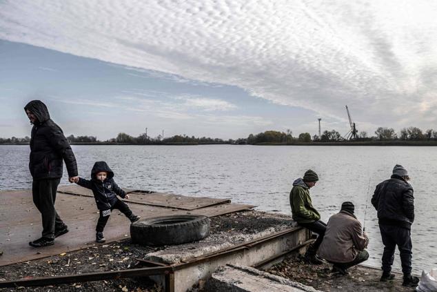 Un hombre pesca mientras la gente disfruta de un día soleado junto al río Dnipro en la recién liberada Jersón, el 14 de noviembre de 2022.