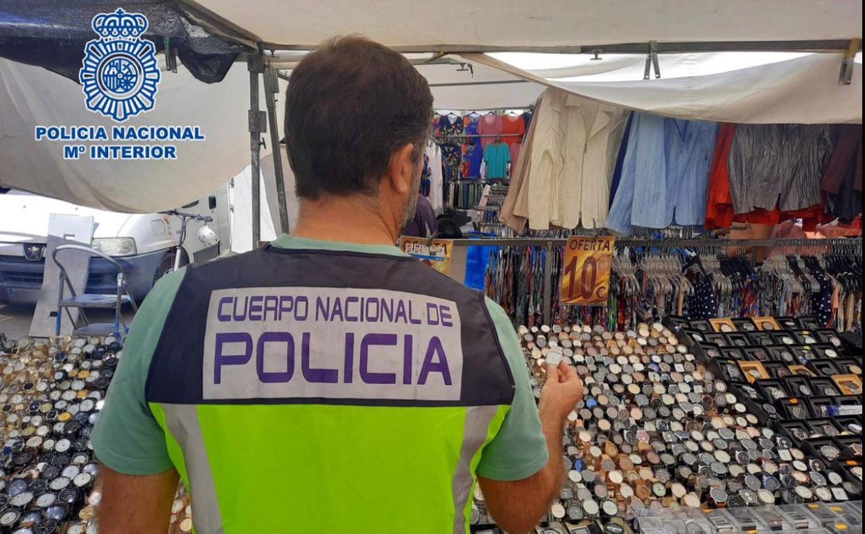 Uno de los agentes frente a un expositor de estos relojes en uno de los puestos del mercadillo del Rincón de Loix en Benidorm.