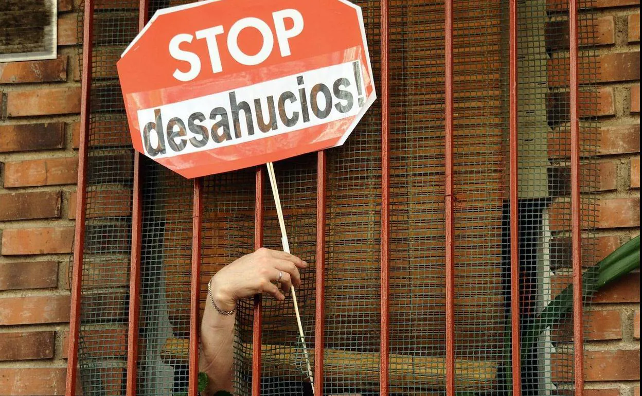 Una mujer sostiene un cartel de «Stop Desahucios» en una vivienda de Madrid. 