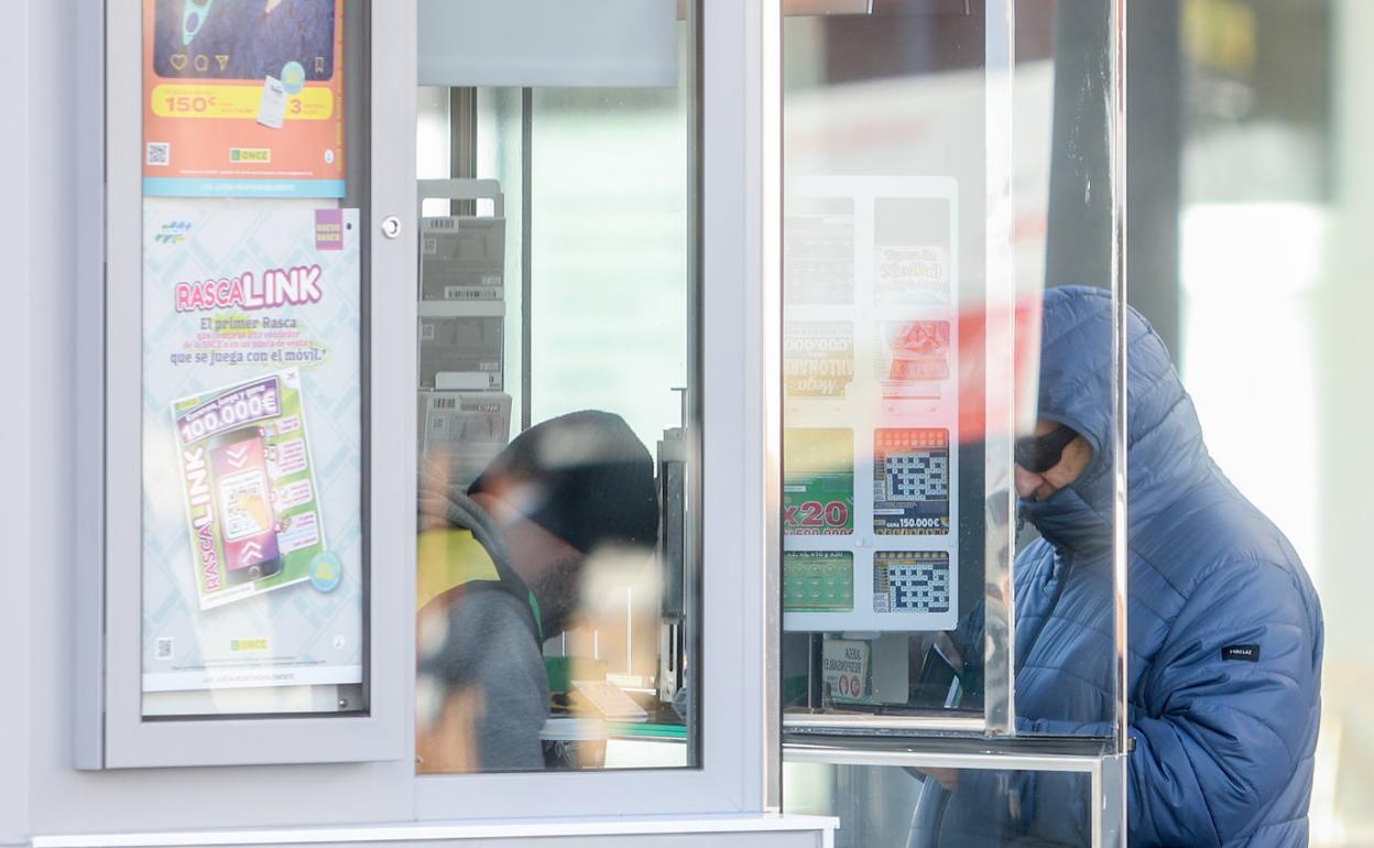 Un hombre abrigado compra un boleto de lotería