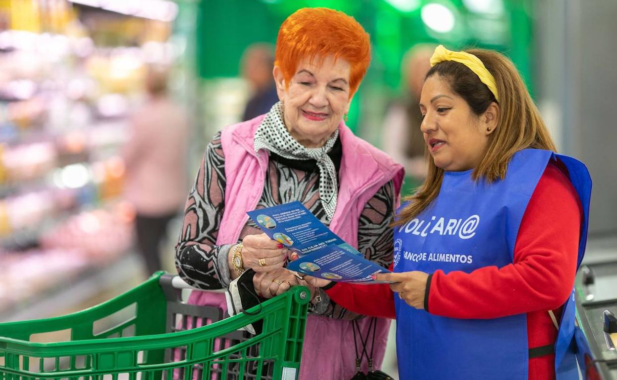 Una voluntaria del Banco de Alimentos explica a una clienta la acción solidaria.
