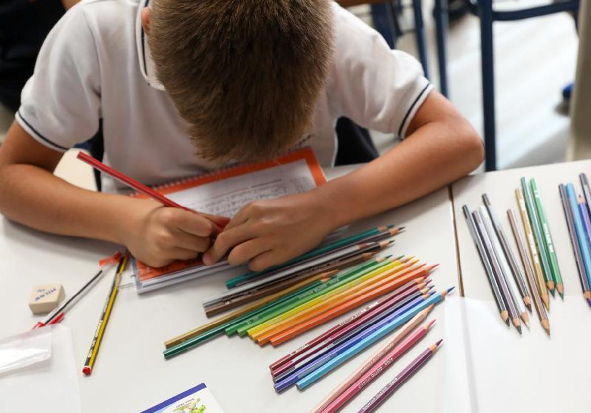 Un niño colorea el día del inicio del curso en el colegio.