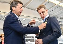 El presidente del PPCV, Carlos Mazón, engalanada la chaqueta de Núñez Feijóo con una palma blanca, detalle de Pikolinos.