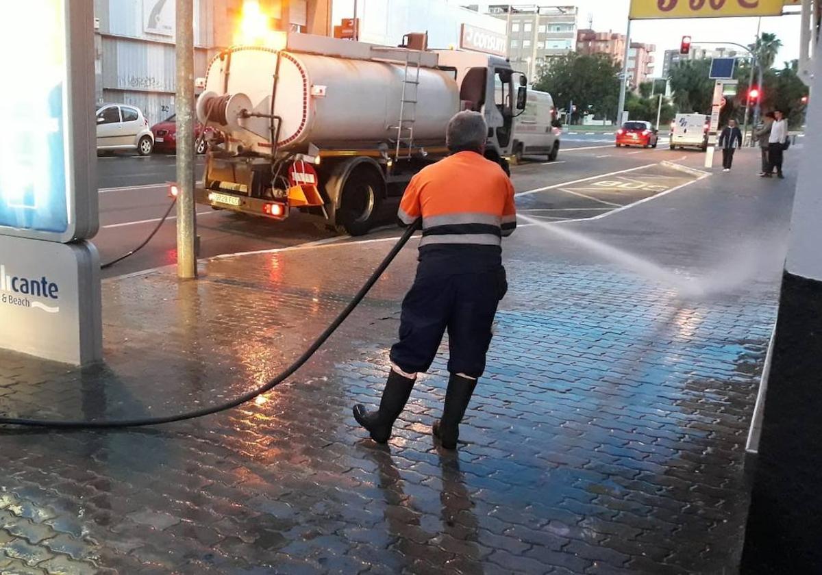 Un operario de limpieza baldea las aceras con el camión cisterna.