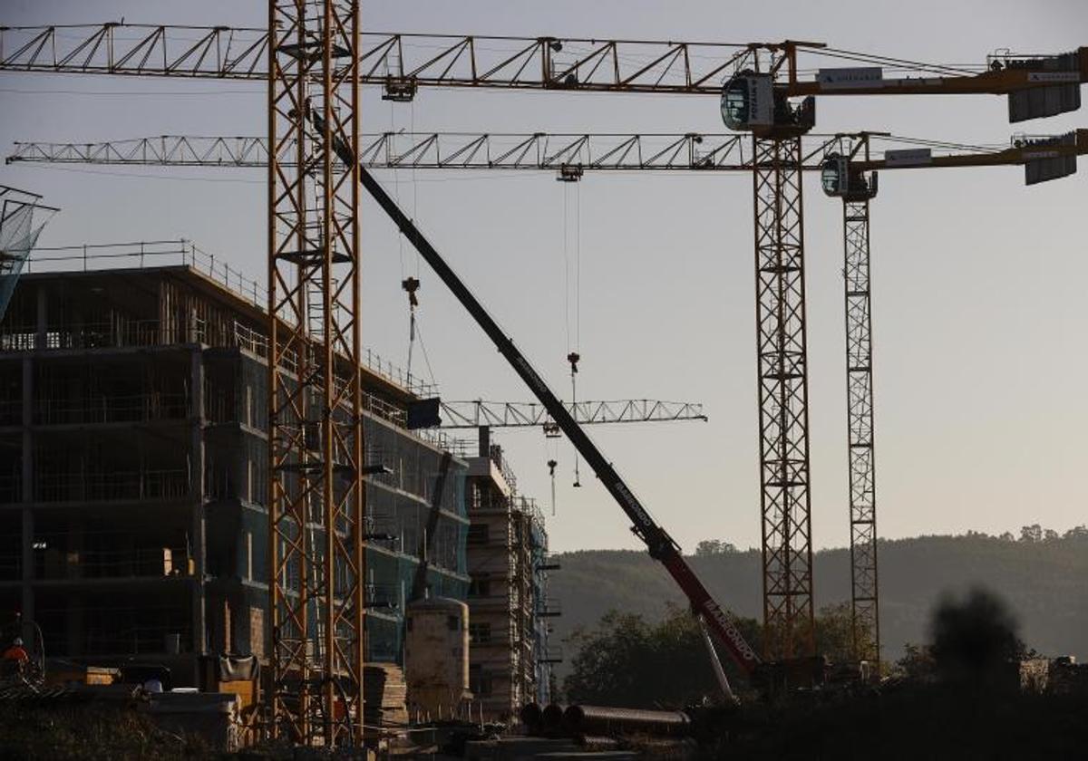 Varias grúas se alzan sobre un edificio de viviendas en construcción.