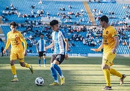 El extremo blanquiazul Luque, entre dos jugadores del Olot
