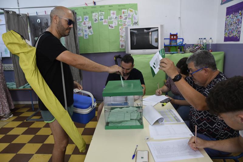 Un hombre cargado con nevera y sombrilla de playa ejerce su derecho al voto