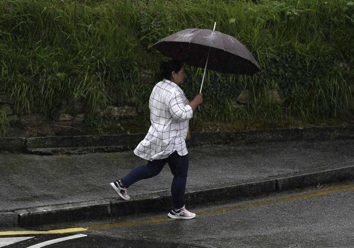 Una mujer se protege de la lluvia con un paraguas.