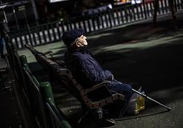 Un pensionista toma el sol en un parque.