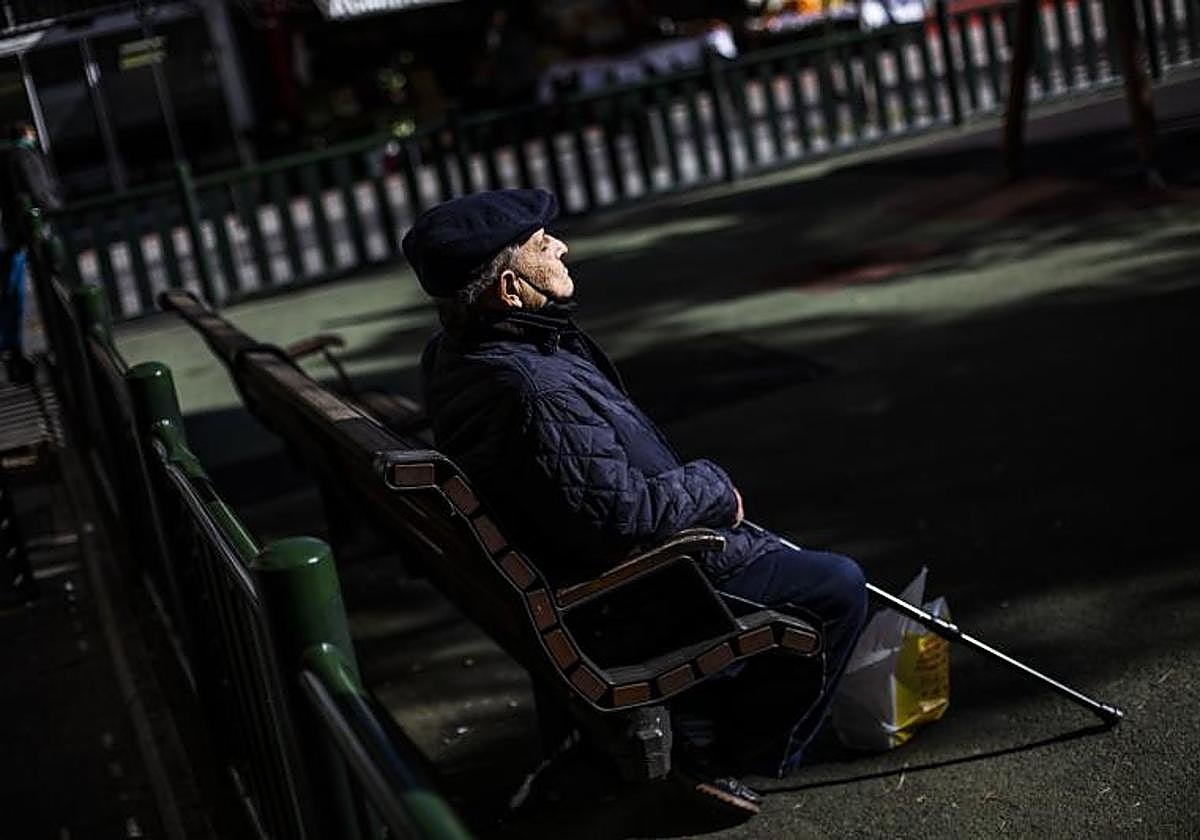 Un pensionista toma el sol en un parque.