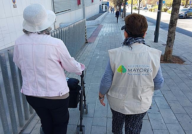 Una asociada acompaña a una persona mayor de plaza América.