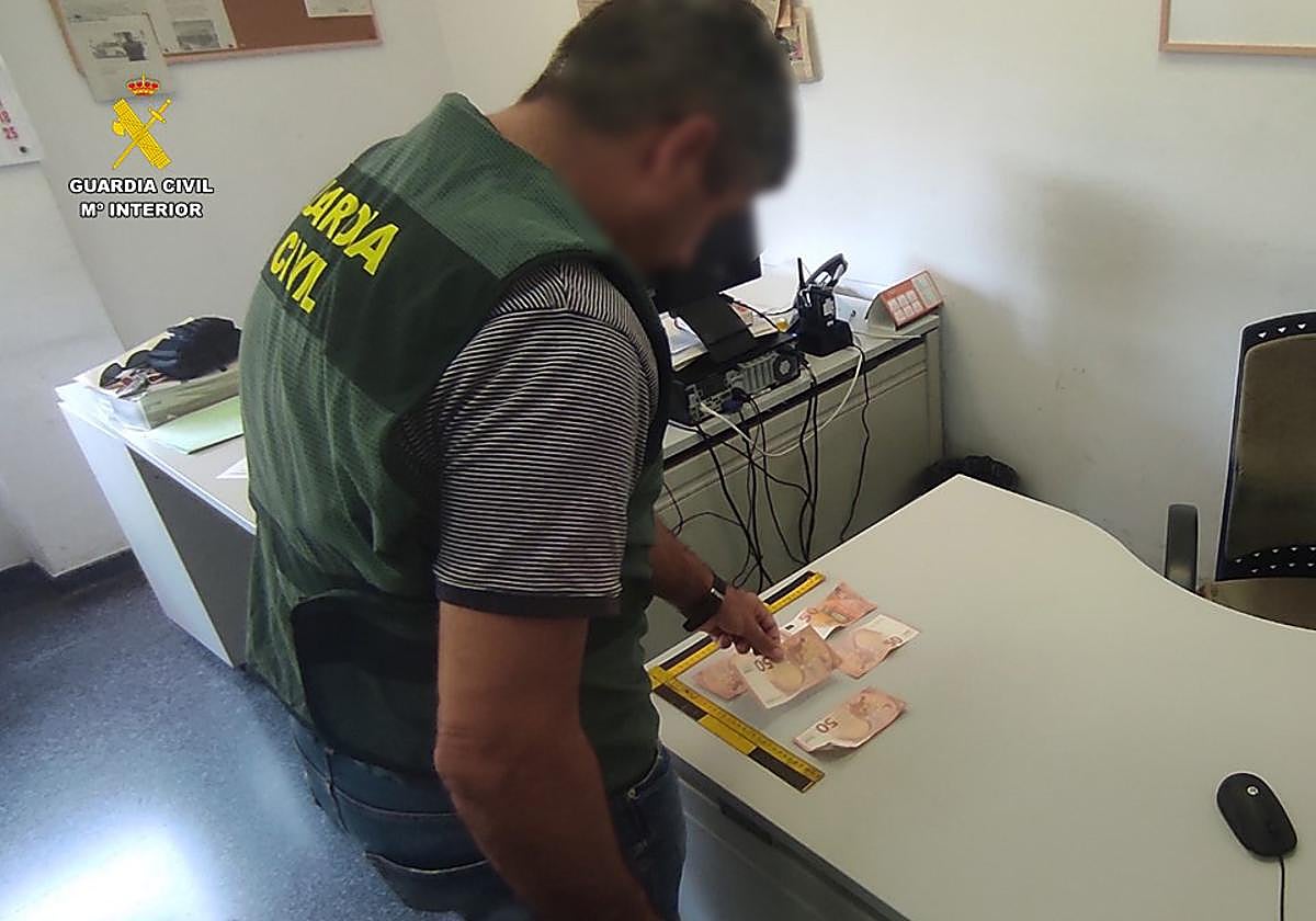 Un agente de la Guardia Civil con los billetes incautados.
