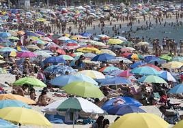La playa llena de sombrillas.
