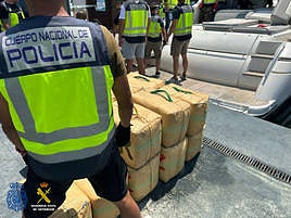 Los agentes con los fardos de droga intervenidos en el puerto de Santa Pola.
