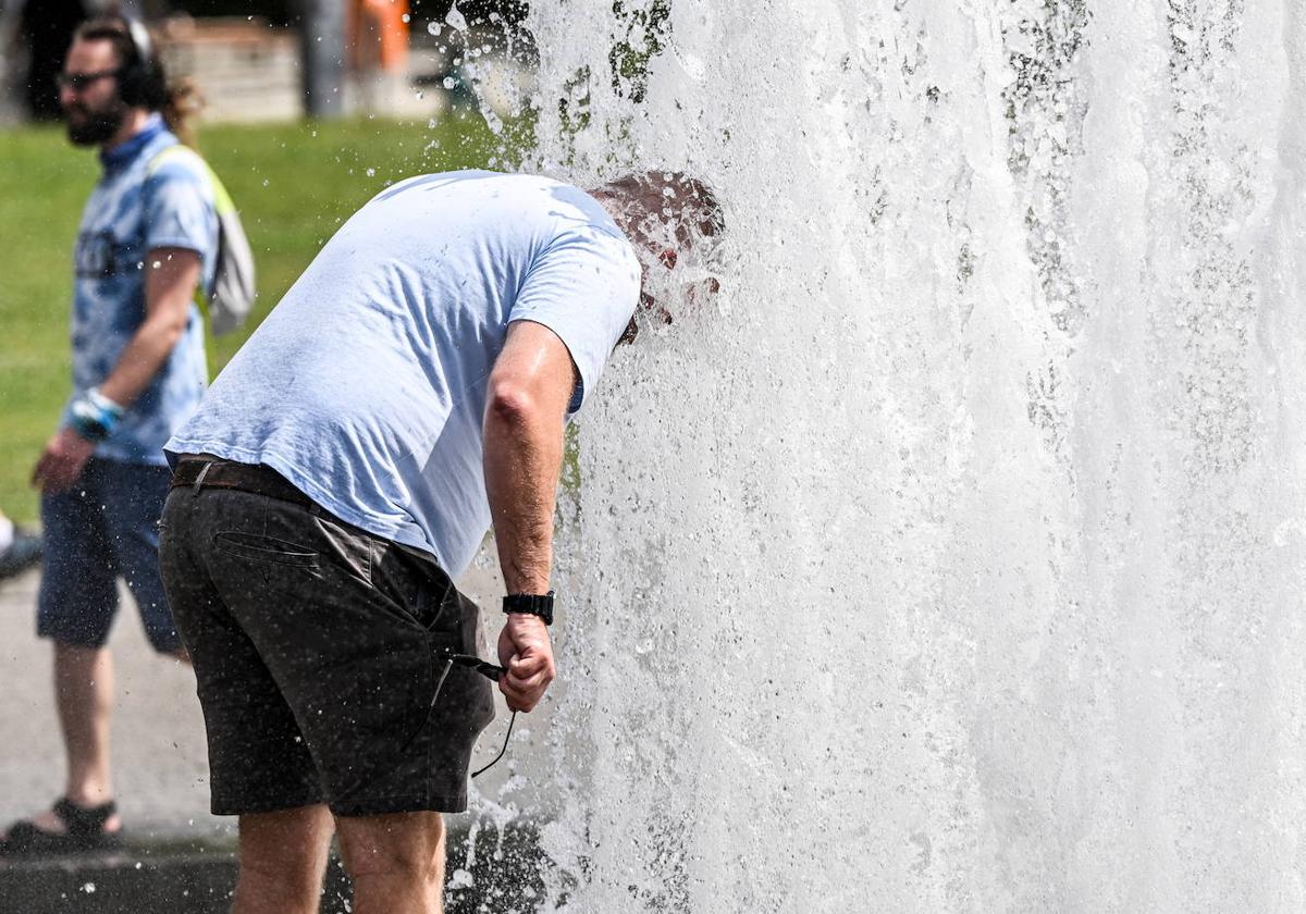 Un hombre se refresca en una fuente ante el inteso calor.