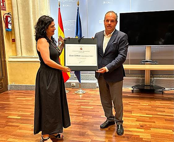 La secretaria de Estado de Migraciones, Isabel Castro, entrega el reconocimiento a Carlos Baño.