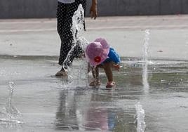 Una niña se refresca en una fuente