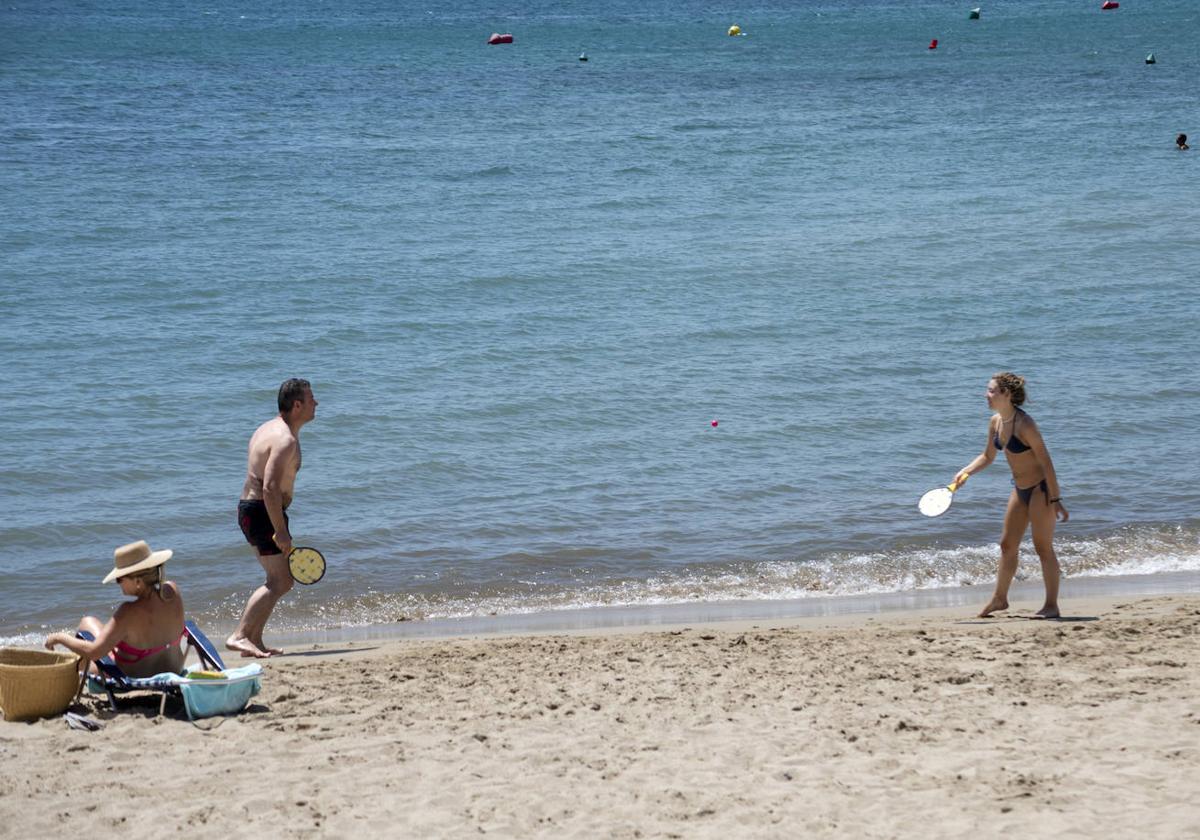 Dos personas juegan a las palas en una playa de Alicante.