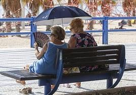 Señoras y abanico y parasol en el paseo del Postiguet de Alicante.