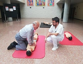 Un hombre realiza un simulacro de RCP ante la mirada de un facultativo.