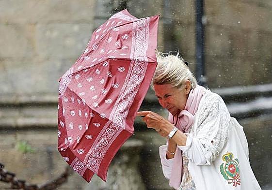 Una mujer se protege del viento y la lluvia.