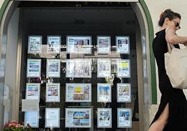 Una joven pasea frente a un portal de alquileres.