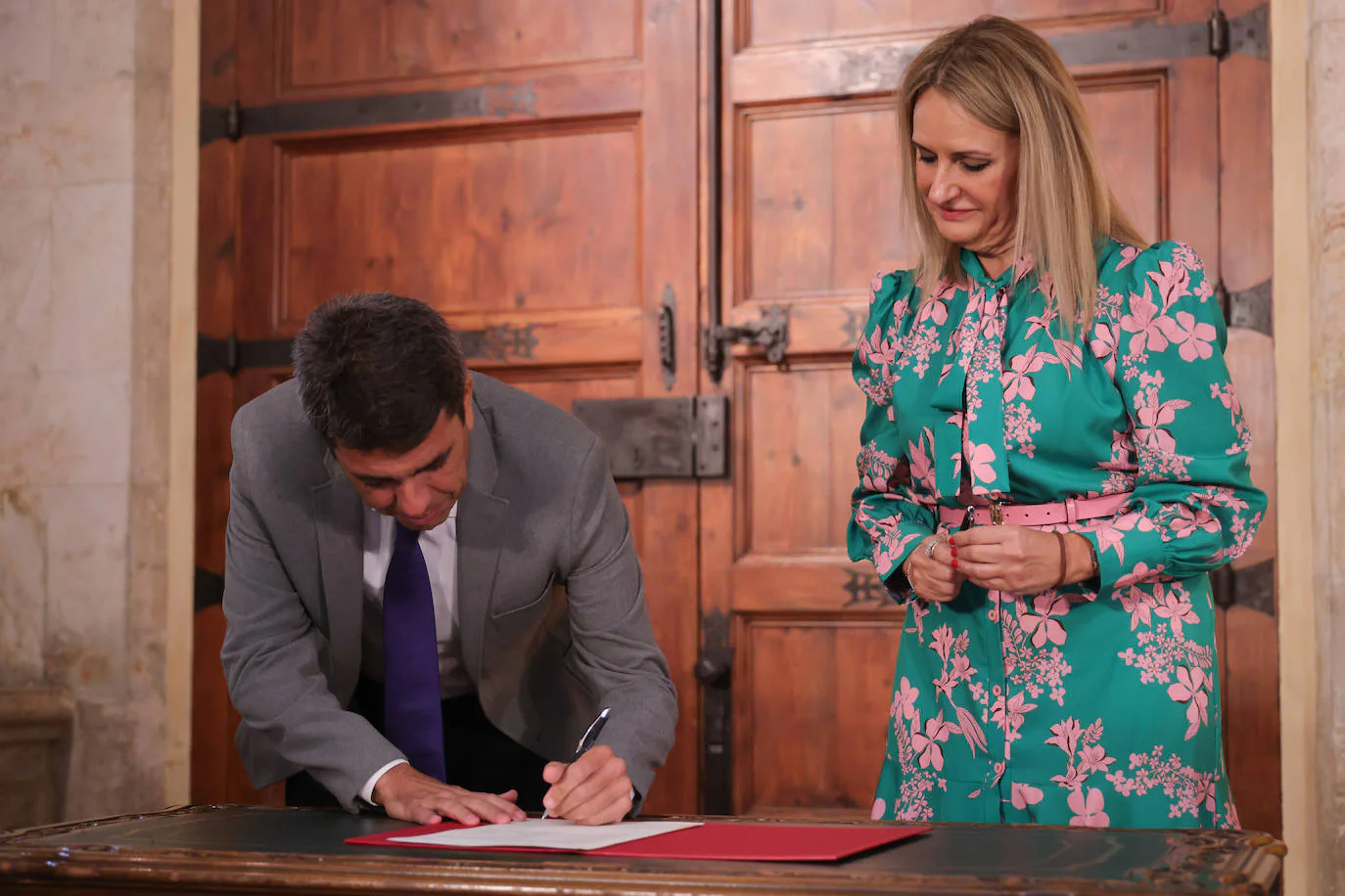 Carlos Mazón firma el decreto-ley ante la mirada de la consellera Nuria Montes.