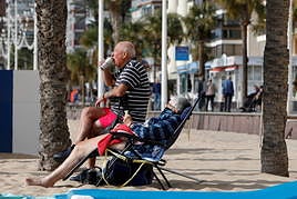 Dos turistas disfrutan del sol y una bebida en la playa de Benidorm.