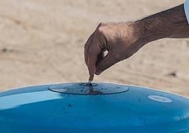 Un hombre apaga su cigarrillo en una papelera en Urbanova.