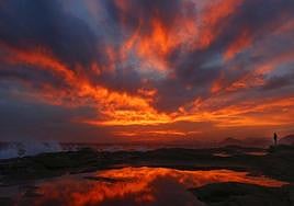 Una joven mira el anochecer y las olas este jueves, en el Cabo de las Huertas de Alicante.