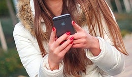Una adolescente haciendo uso de un teléfono móvil.