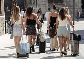 Un grupo de turistas pasea con sus maletas.