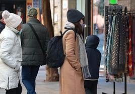 Una persona abrigada observa un puesto de bufandas.