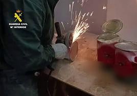 Agente de la Guardia Civil abre las latas de tomate con marihuana dentro.