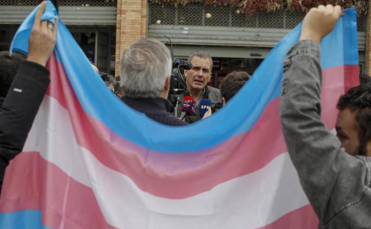 Dos activistas transgénero muestran la bandera del orgullo trans a Ortega Smith, durante su visita a Alicante.