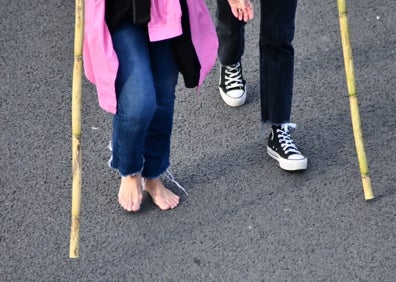 Imagen secundaria 1 - Varios peregrinos caminan descalzos sobre el asfalto.