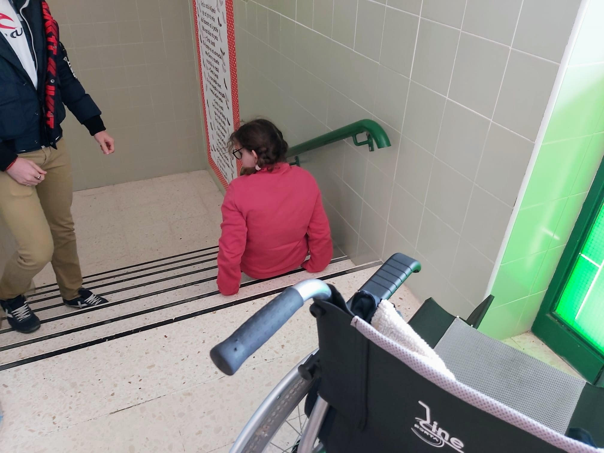 Una alumna baja unas escaleras a culadas.