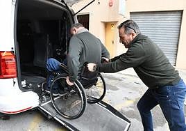 El conductor de un taxi adaptado ayuda a subir a uno de estos vehículos a una persona en silla de ruedas.