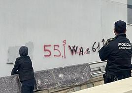 Uno de los menores limpia su grafiti ante la supervisión de un agente.