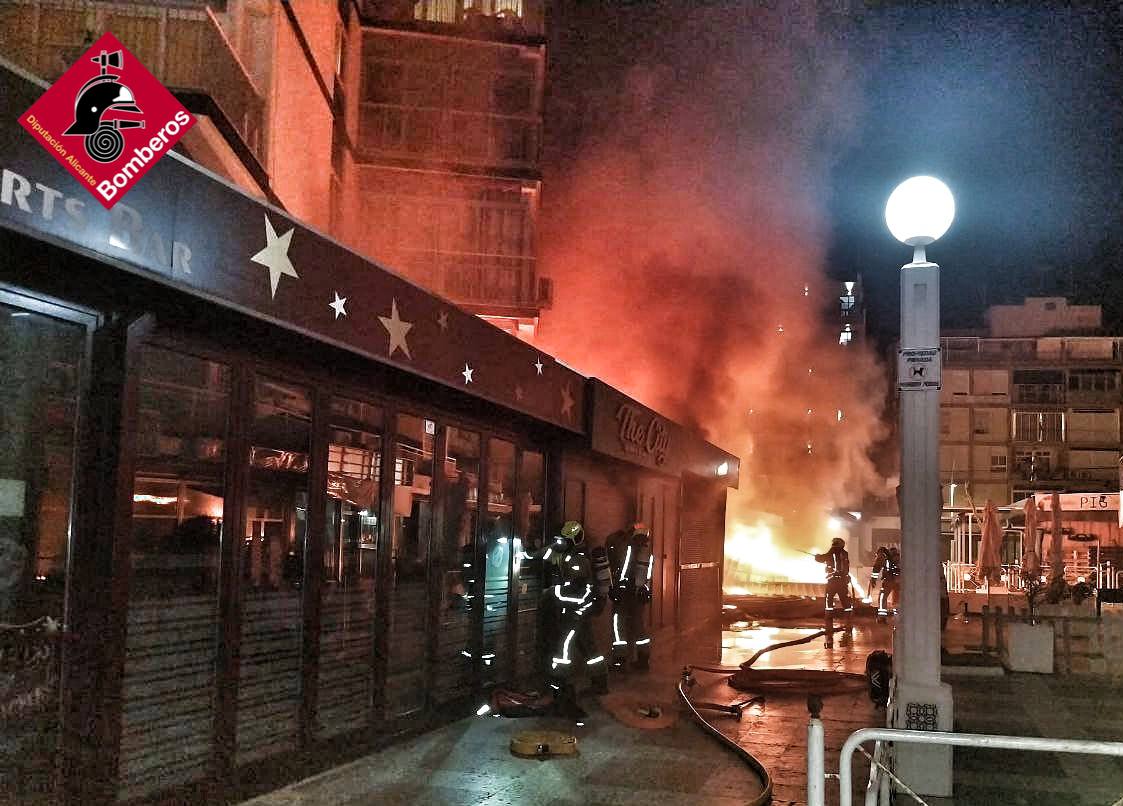 Los bomberos luchan contra las llamas que devoran el local comercial.