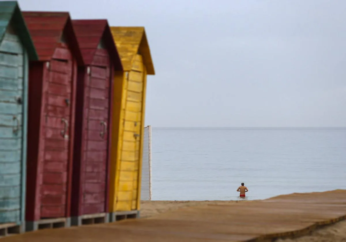 Un hombre se baña en la playa de San Juan a pesar de la fina lluvia que caía este viernes.