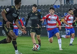 Pol Roigé conduce la pelota ante un rival del Granada B durante el partido de esta noche en el Antonio Solana.