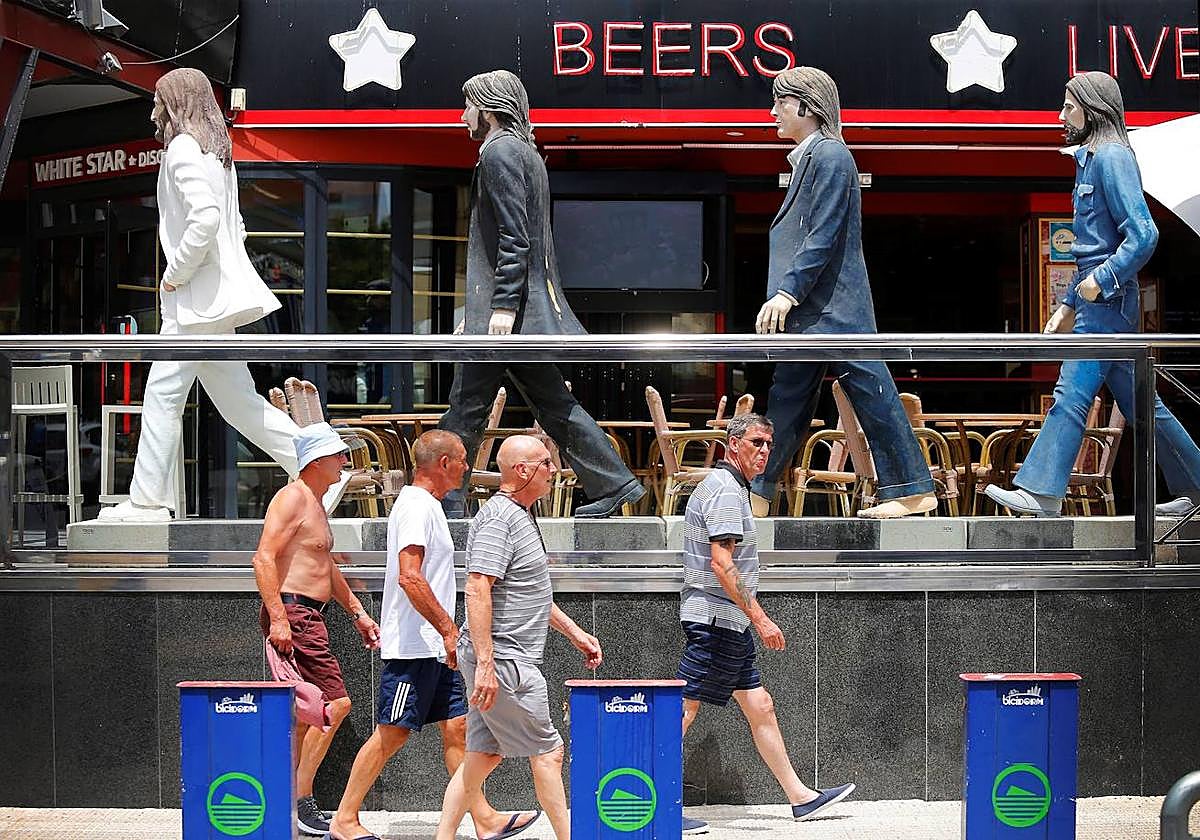 Turistas bajo las figuras de los Beatles en Benidorm.