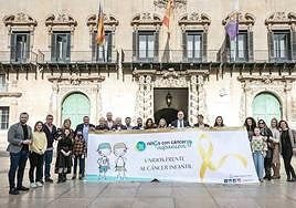 Despliegue de una gran pancarta con un lazo dorado en la plaza del Ayuntamiento