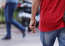 Un hombre fuma un cigarro en la calle.