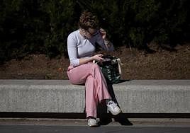 Una mujer lee noticias en un móvil.