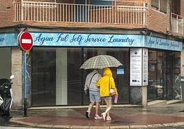 Dos personas se refugian de la lluvia bajo un paraguas.