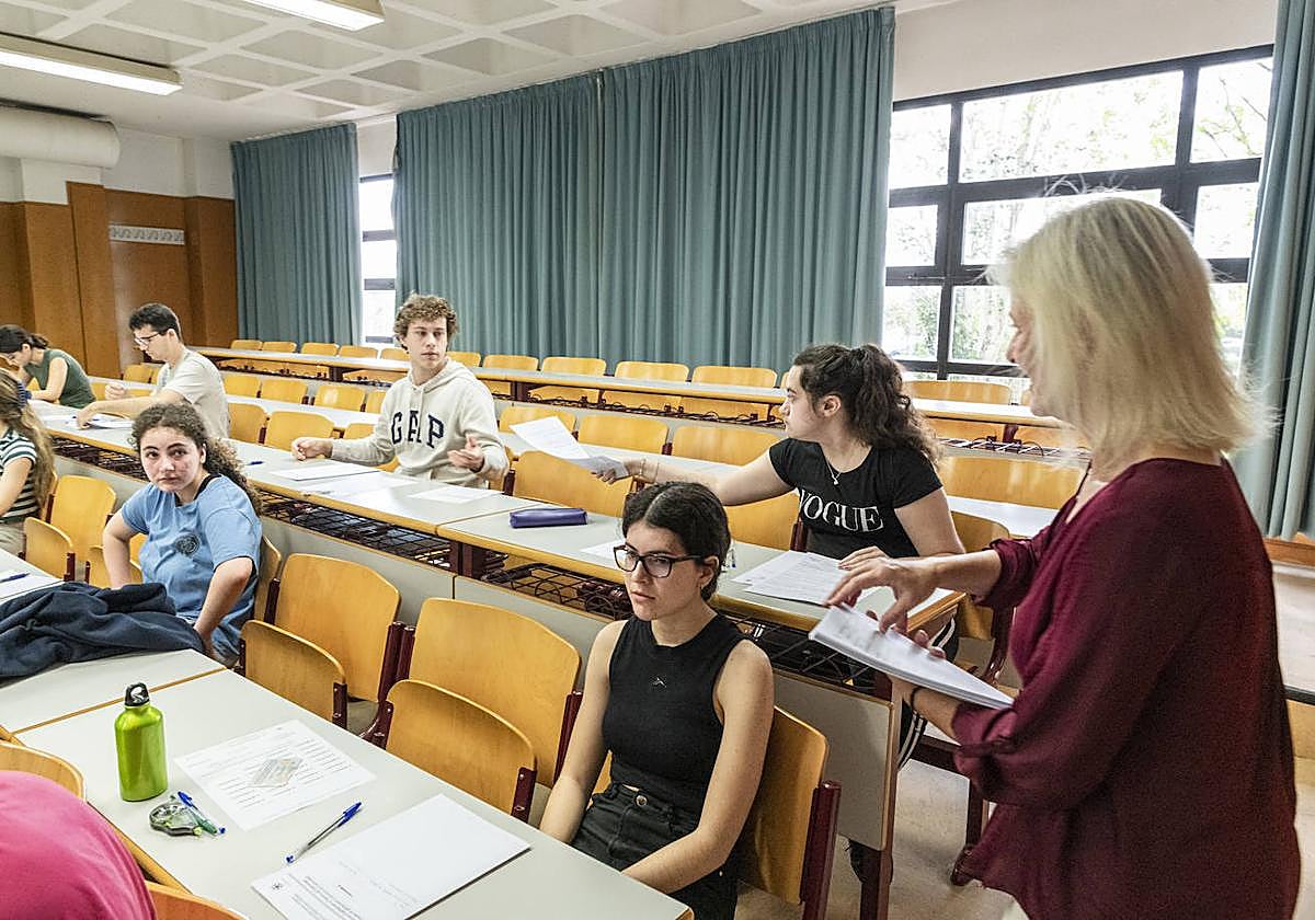 Docente repartiendo exámenes de Selectividad en una aula de Alicante.