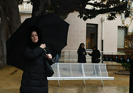 Una mujer sostiene un paraguas ante el paso de la procesión cancelada este lunes en Alicante.