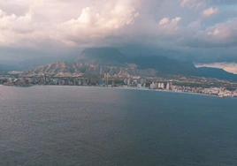 Imagen de la bahía de Benidorm con las nubes cubriendo el Puig Campana